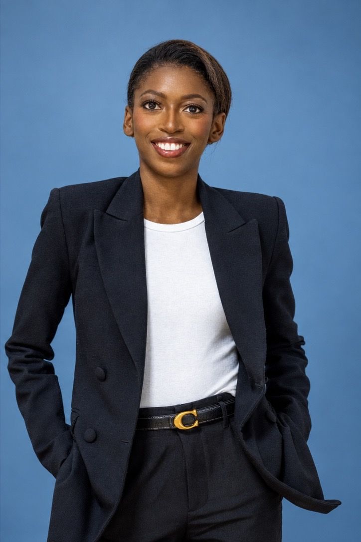 Naledi Ncube, smiling, in a navy suit against a blue backdrop