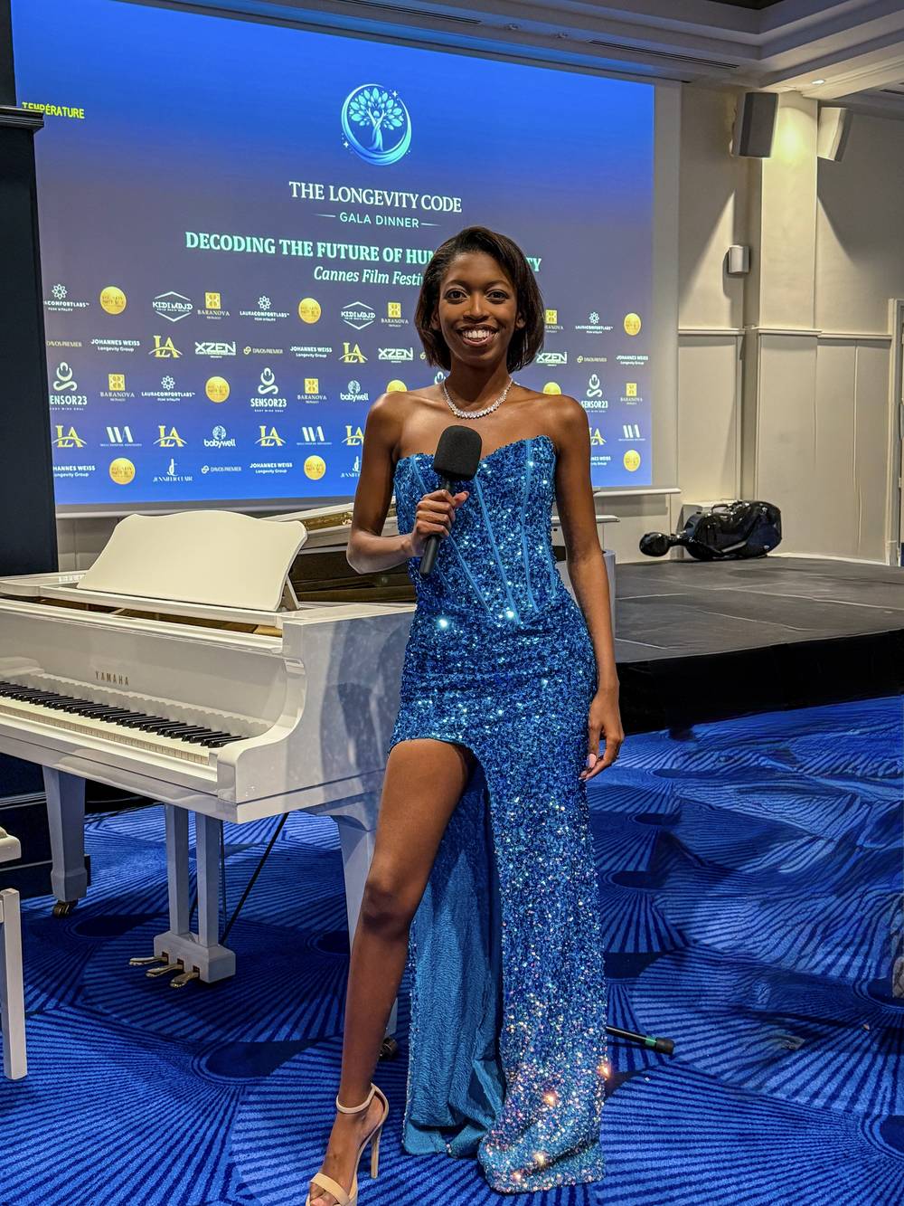 Naledi Ncube holding a microphone on stage at The Longevity Code Gala Dinner